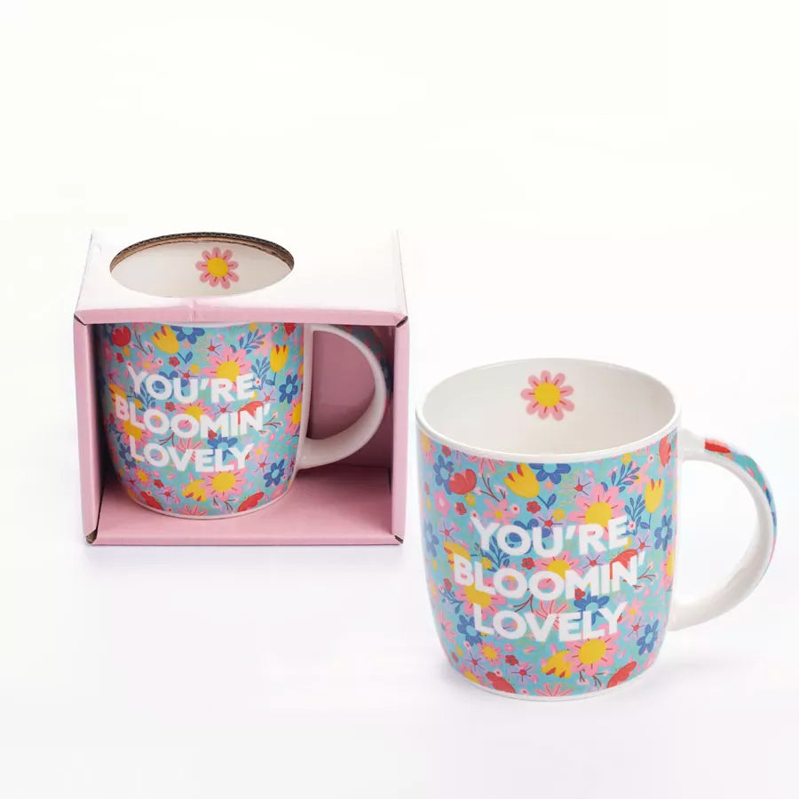 Tiger Feet "You're Blooming Lovely" mug featuring colorful floral design and playful tiger feet logo on white ceramic.