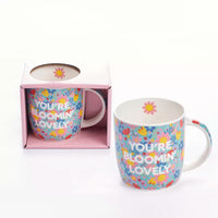 Tiger Feet "You're Blooming Lovely" mug featuring colorful floral design and playful tiger feet logo on white ceramic.